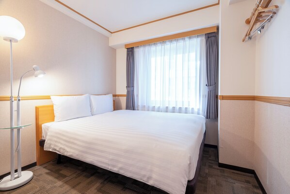 A hotel room with a large bed, a bedside lamp, a window with curtains, and a wooden headboard. - Toyoko Inn Busan Station No.1 (Busan)