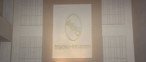 A framed sign with the logo and website 'toyoko-inn.com' on a textured wall.