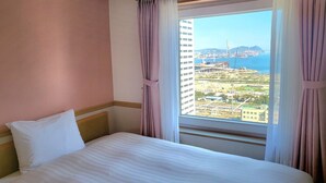 A hotel room with a bed, a view of a cityscape and a bridge, and a window with curtains. - Toyoko Inn Busan Jungang Station (Busan)