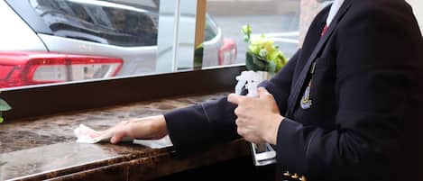 A person cleaning a marble countertop with a cloth and a spray bottle.
