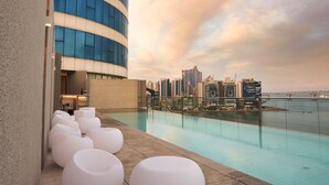 A rooftop pool with white lounge chairs, a city skyline view, and a waterfront. - Hotel Aqua Palace (Busan)