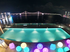 Un espace piscine offrant une vue sur un pont illuminé la nuit.