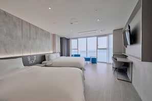 Une chambre d’hôtel moderne dotée de deux grands lits, d’un bureau, d’une télévision et d’un balcon avec vue.