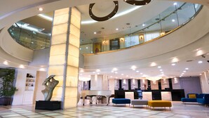 A spacious lobby with a grand piano, seating area, and a reception desk. - Hotel Aqua Palace (Busan)