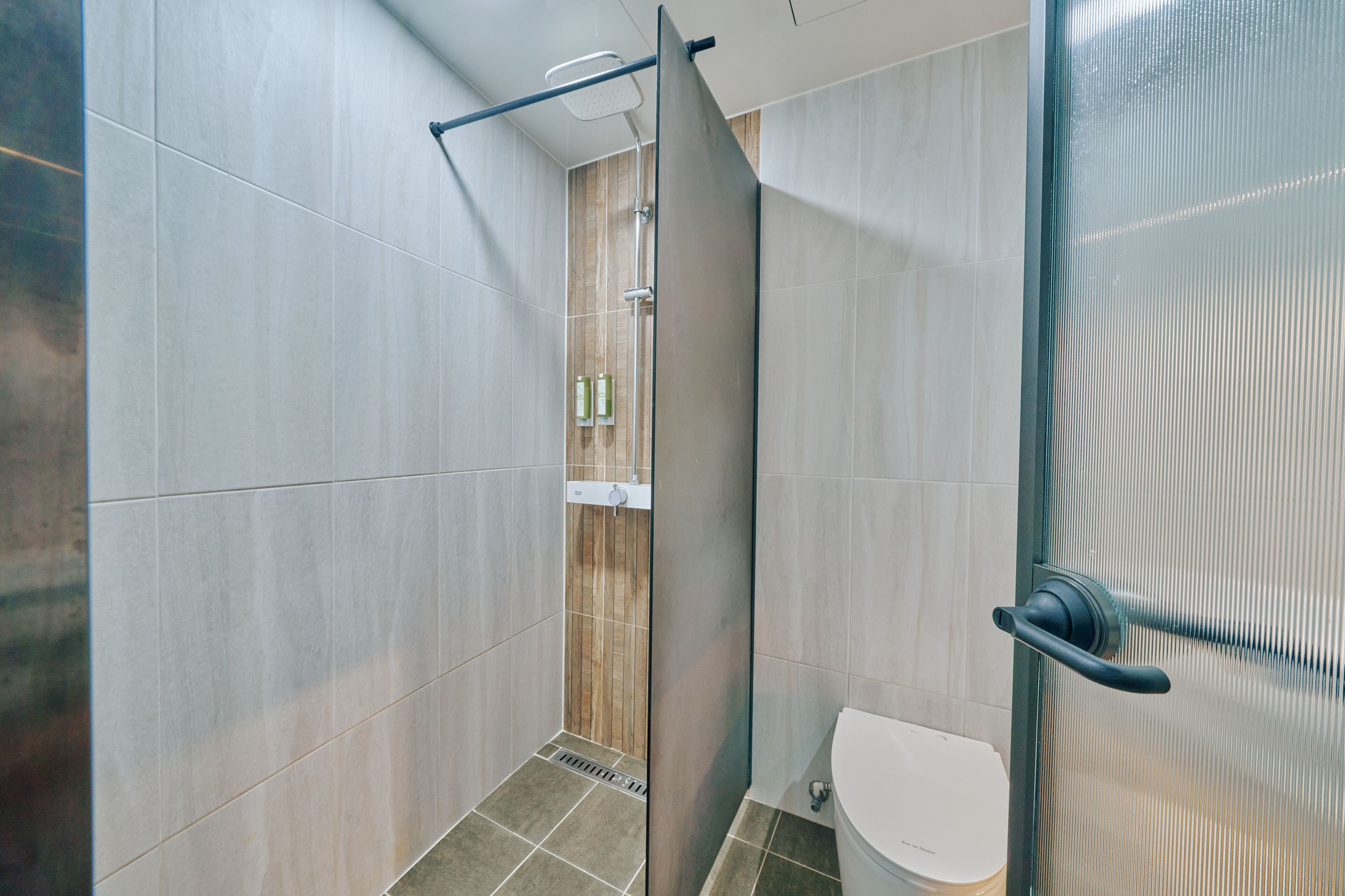 A modern bathroom with a glass shower enclosure, a toilet, and a showerhead.