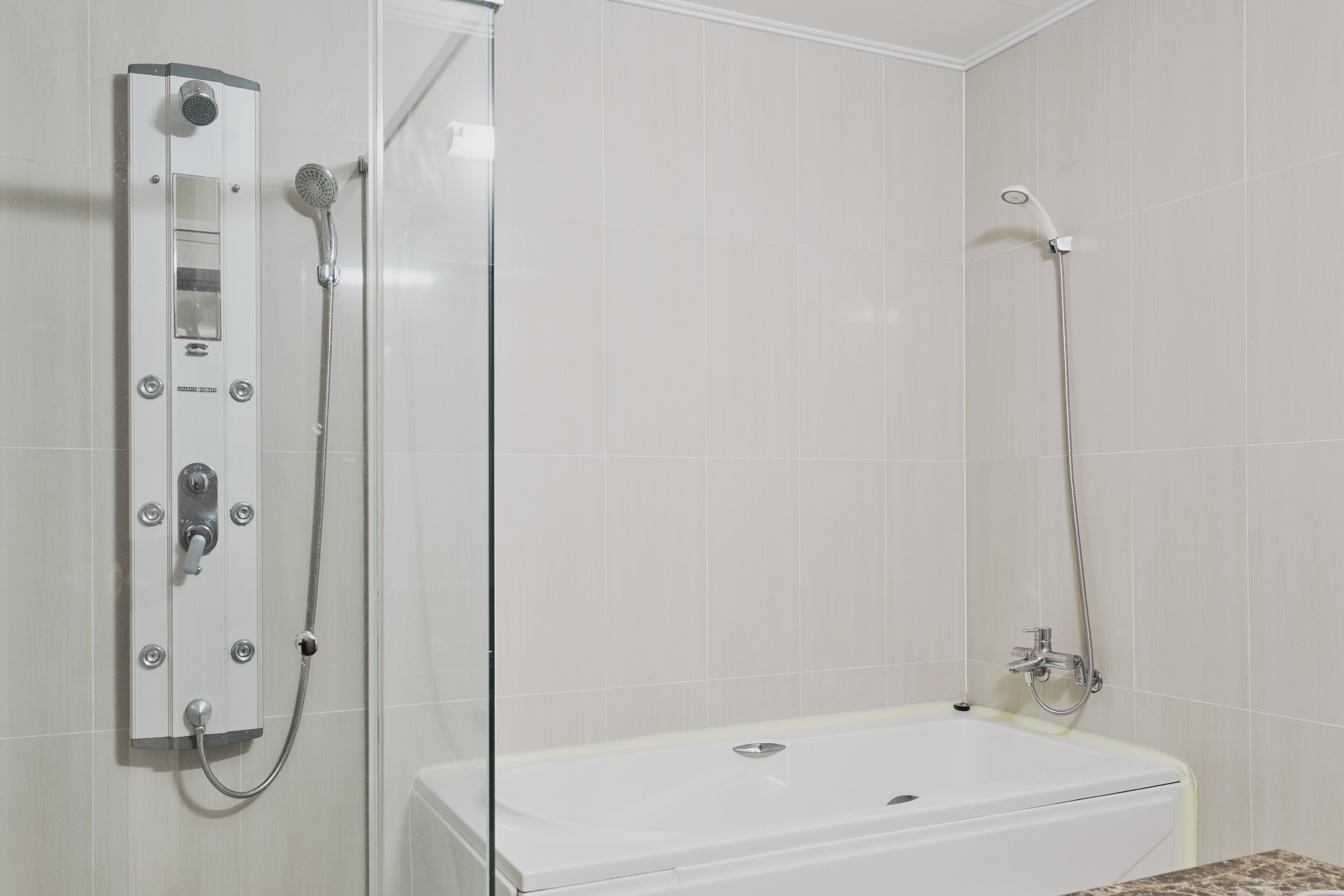 A bathroom with a shower enclosure, a bathtub, and tiled walls.