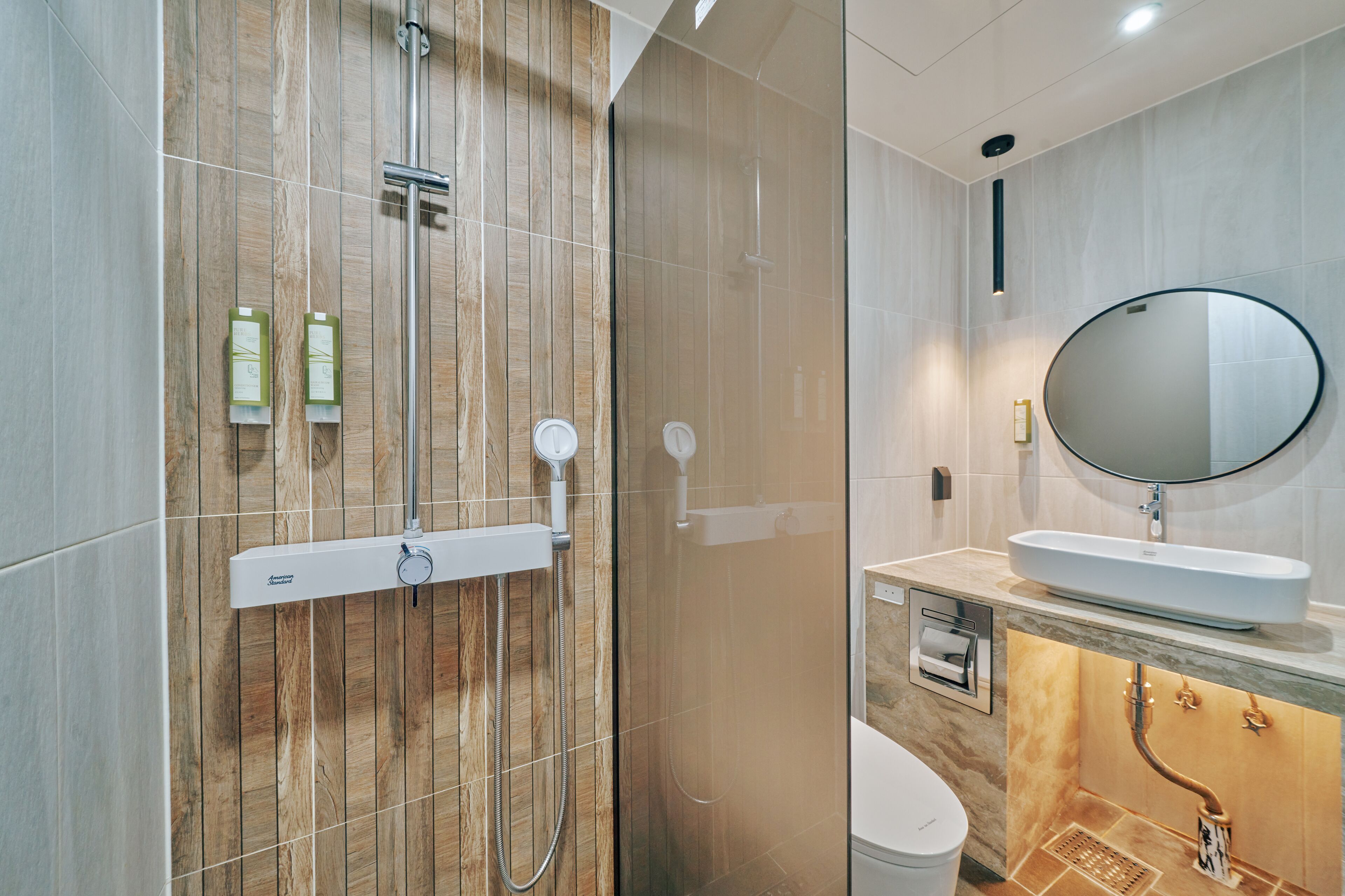 A modern bathroom with a shower, toilet, sink, and mirror.
