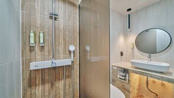 A modern bathroom with a shower, toilet, sink, and mirror.