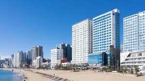 Ein Strandhotel mit mehreren Hochhäusern, einem Sandstrand und blauem Himmel.