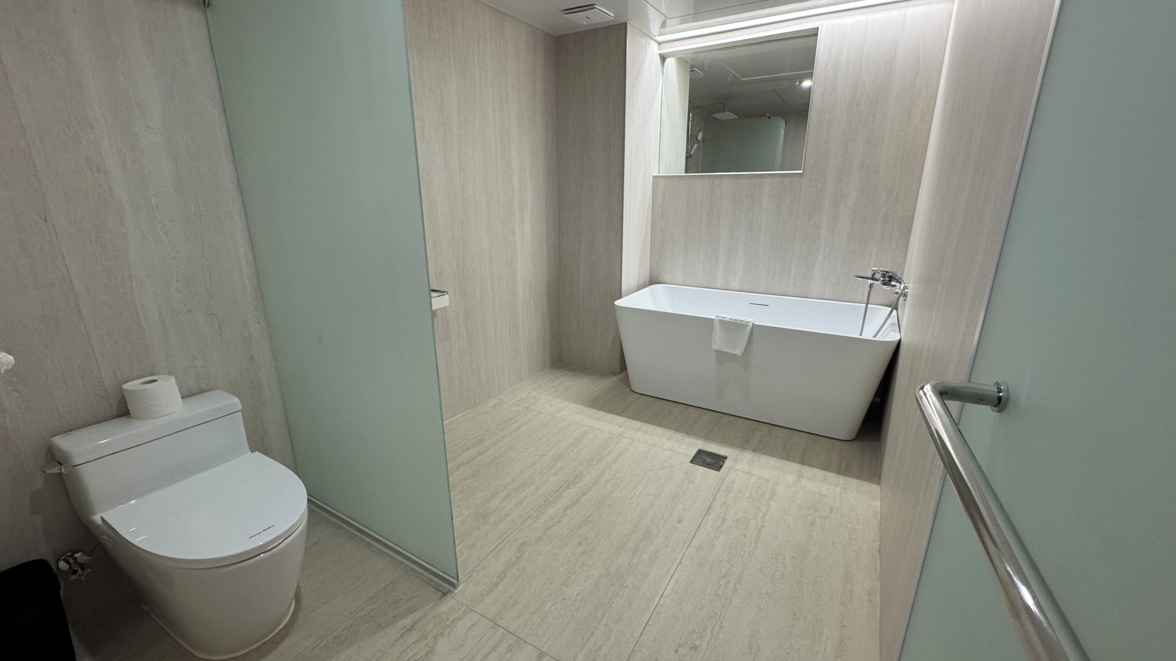 A modern bathroom with a toilet, a bathtub, and a sink.