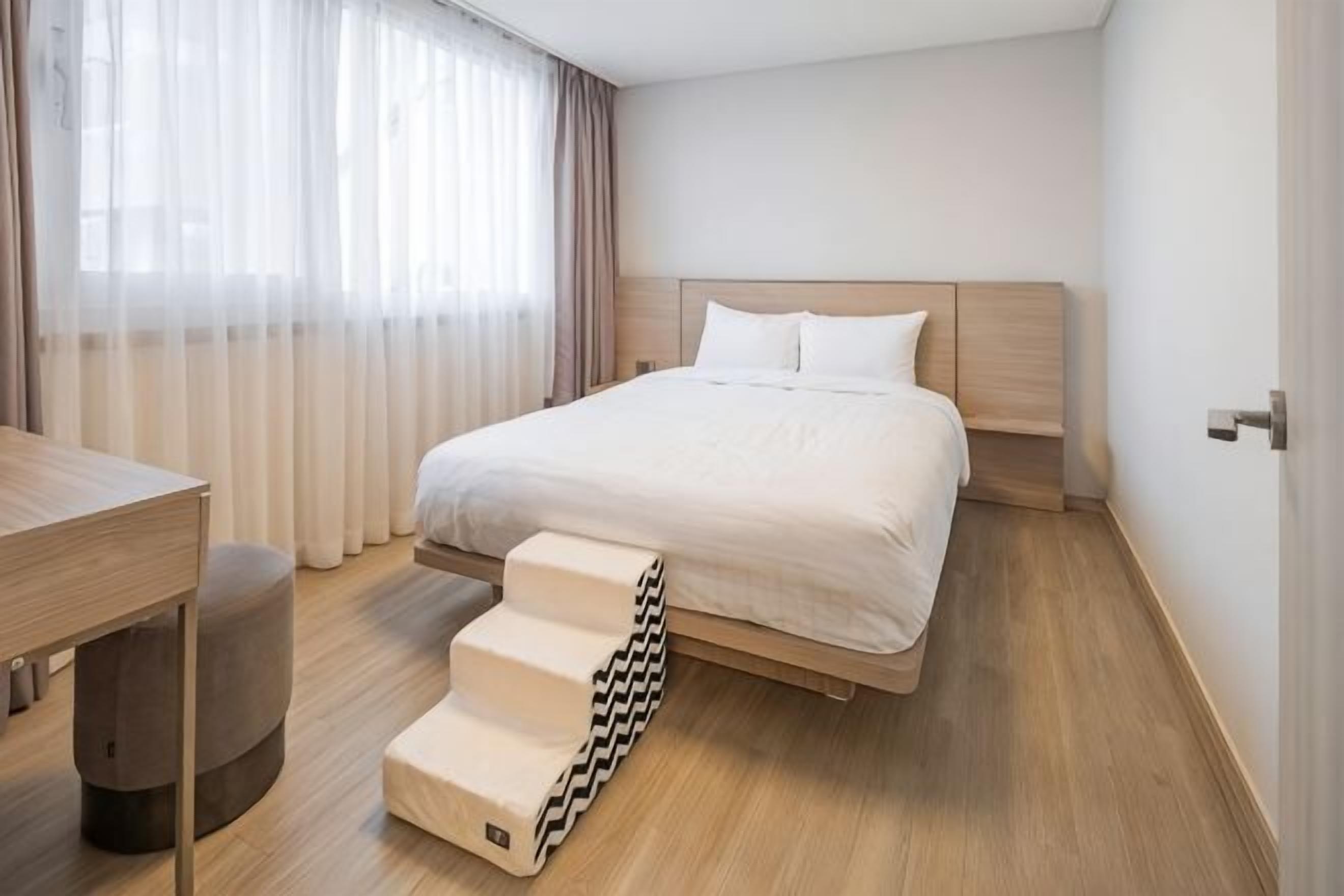 A modern hotel room with a bed, a desk, and a staircase.