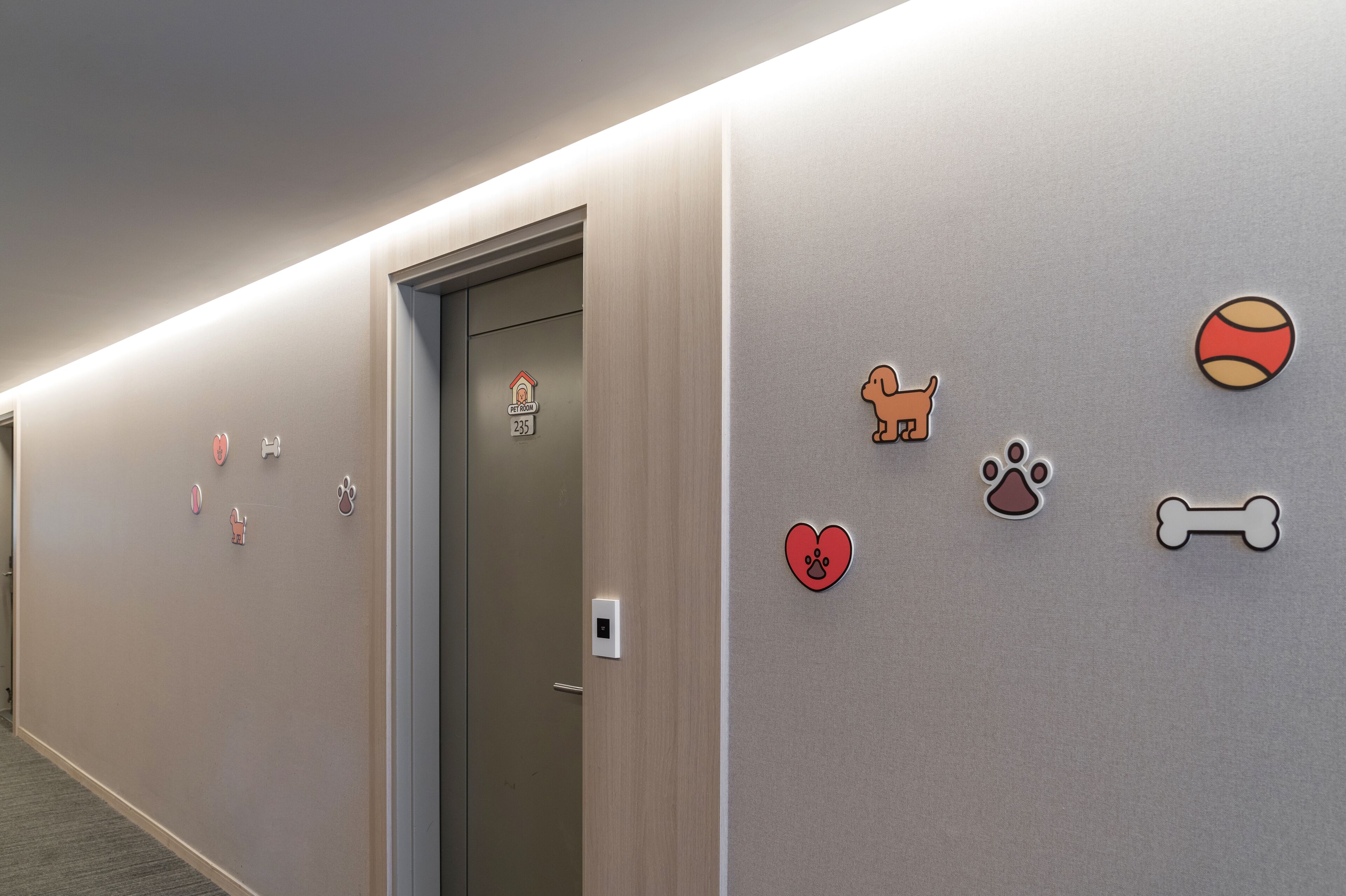 Un pasillo con una puerta que dice 'Home' y una pared decorada con motivos de mascotas.