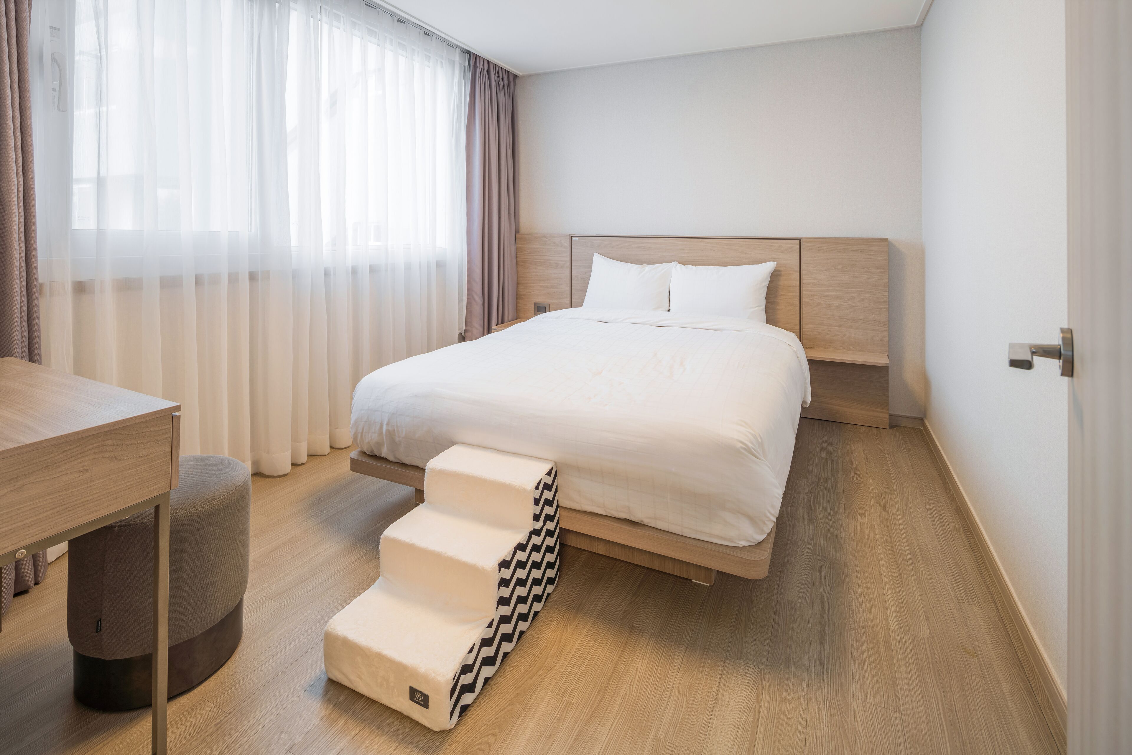 A modern hotel room with a bed, a desk, and a staircase.