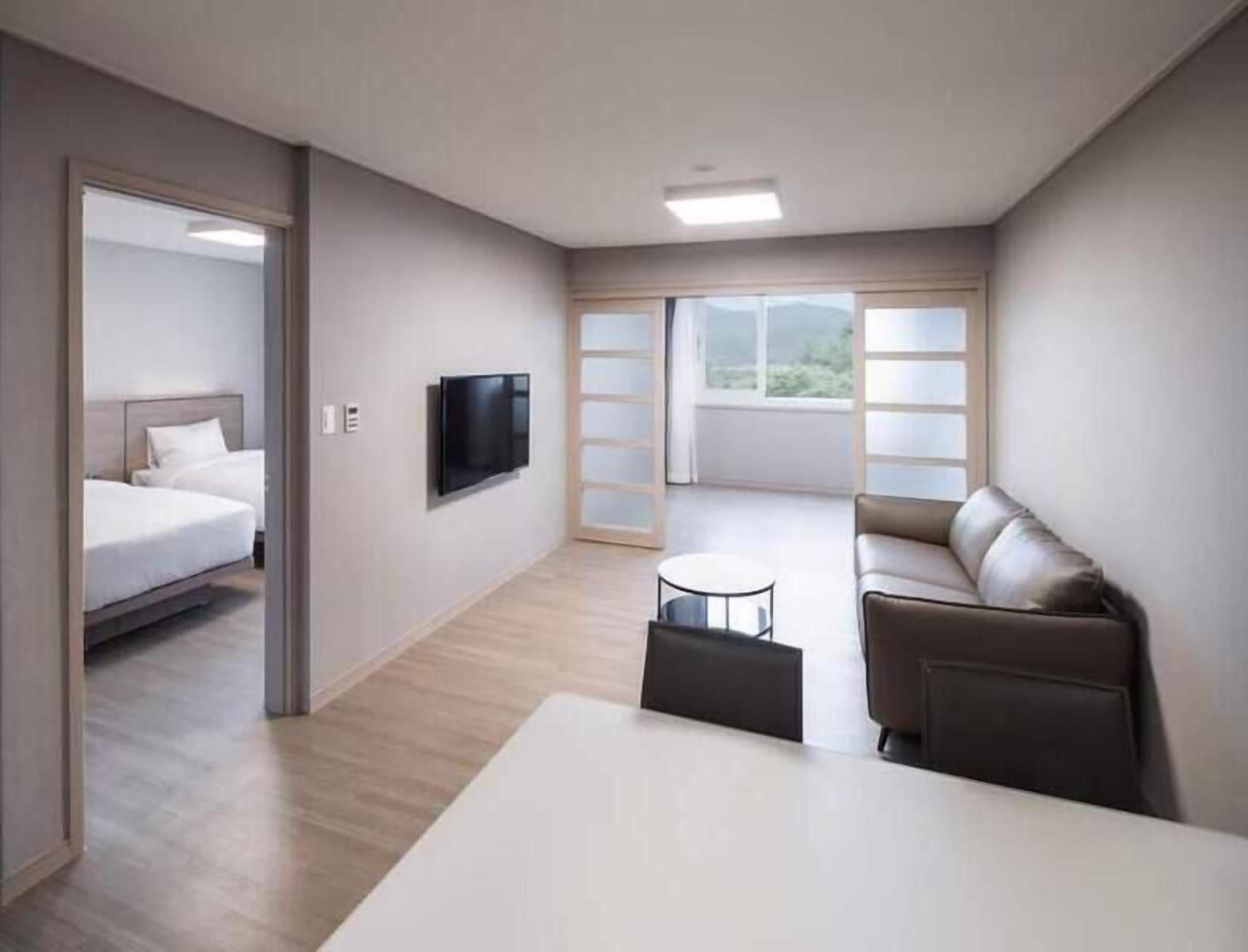 Ett modernt hotellrum med en säng, en TV, en soffa och ett litet bord.