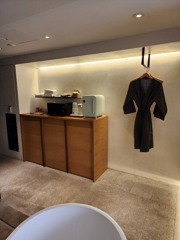 A modern bathroom with a wooden vanity, a white bathtub, and a robe hanging on the wall. - Phoenix Hotel Pyeongchang (Pyeongchang)