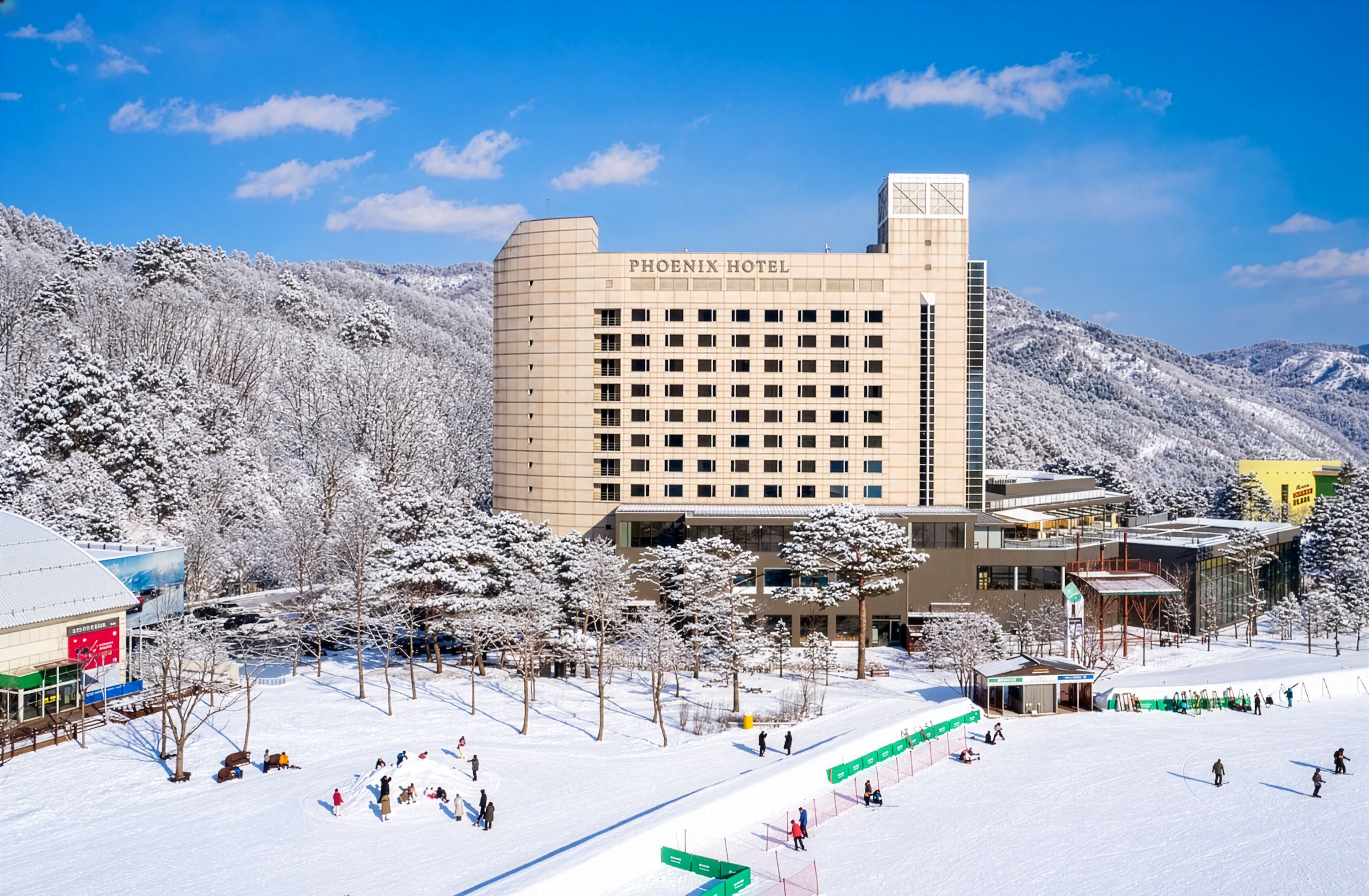 Un hotel amb un disseny modern, envoltat d'arbres i muntanyes cobertes de neu.