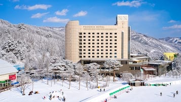 Un hotel amb un disseny modern, envoltat d'arbres i muntanyes cobertes de neu.