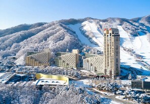A hotel complex with multiple buildings, a ski slope in the background, and a snow-covered landscape.
