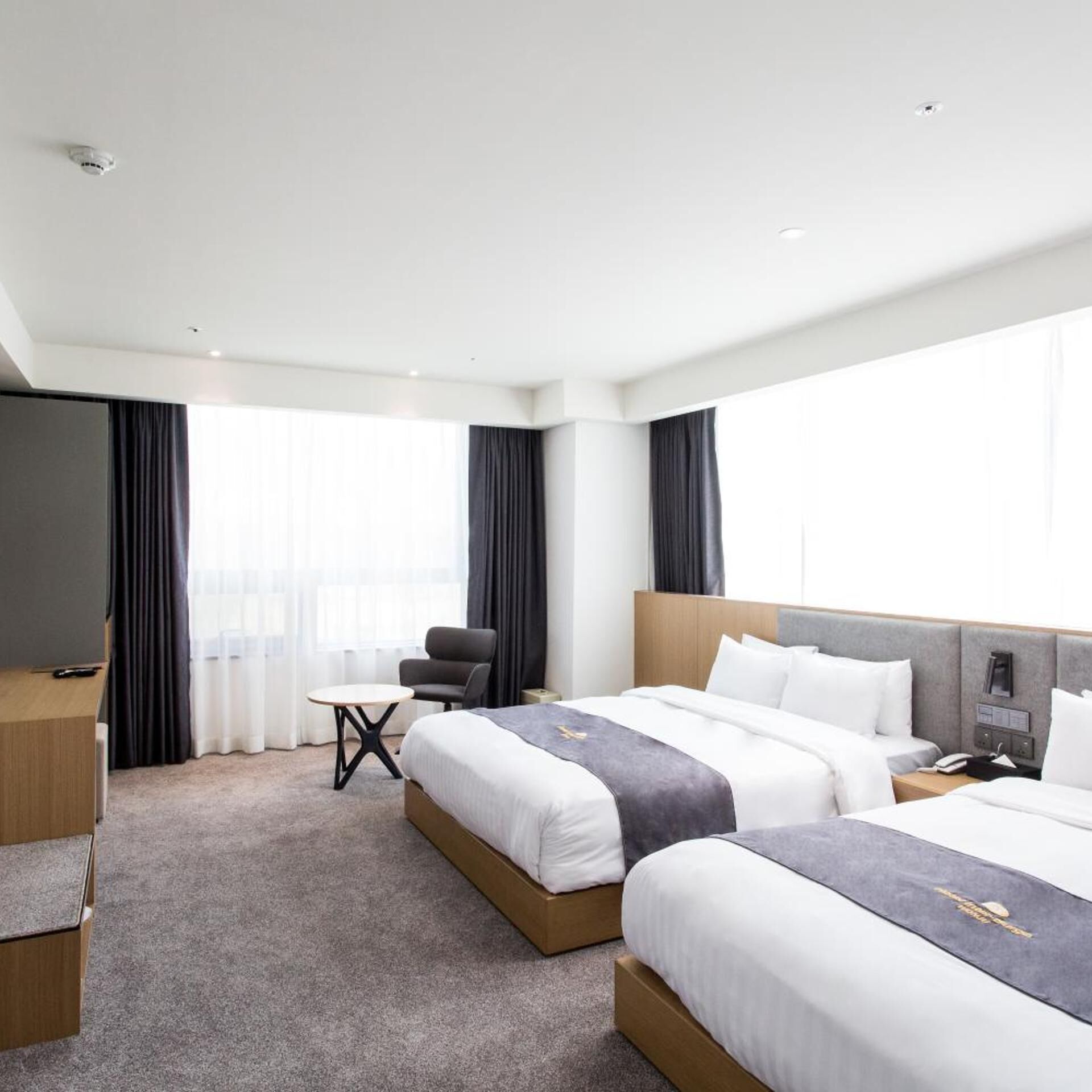Una habitación de hotel con dos camas, un escritorio, una silla y un televisor.