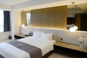 A modern hotel room with a large bed, bedside tables, a mirror, and a vase on the nightstand. - Hotel Inter Burgo Wonju (Wonju)