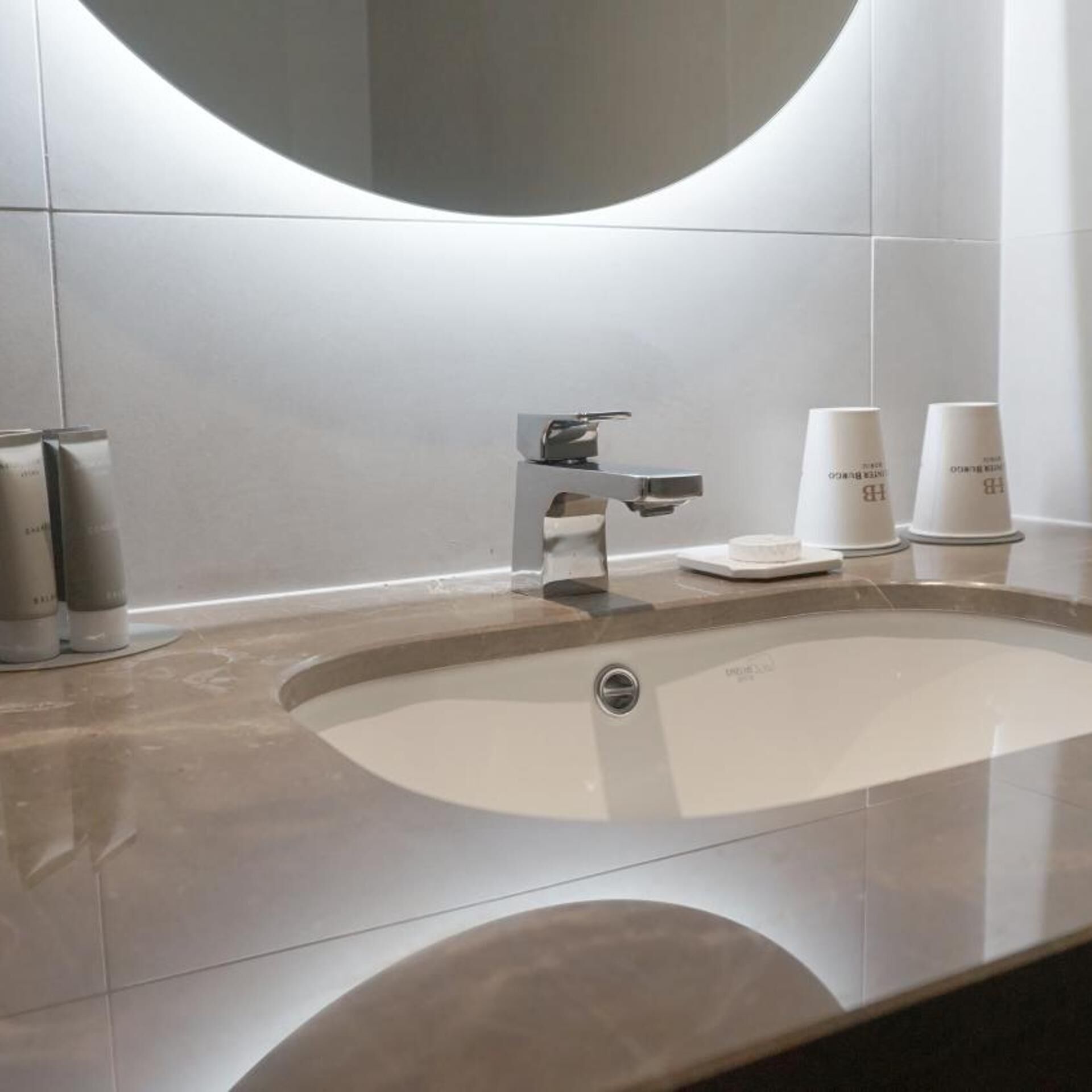 Un baño moderno con un lavabo grande, un espejo y un grifo.