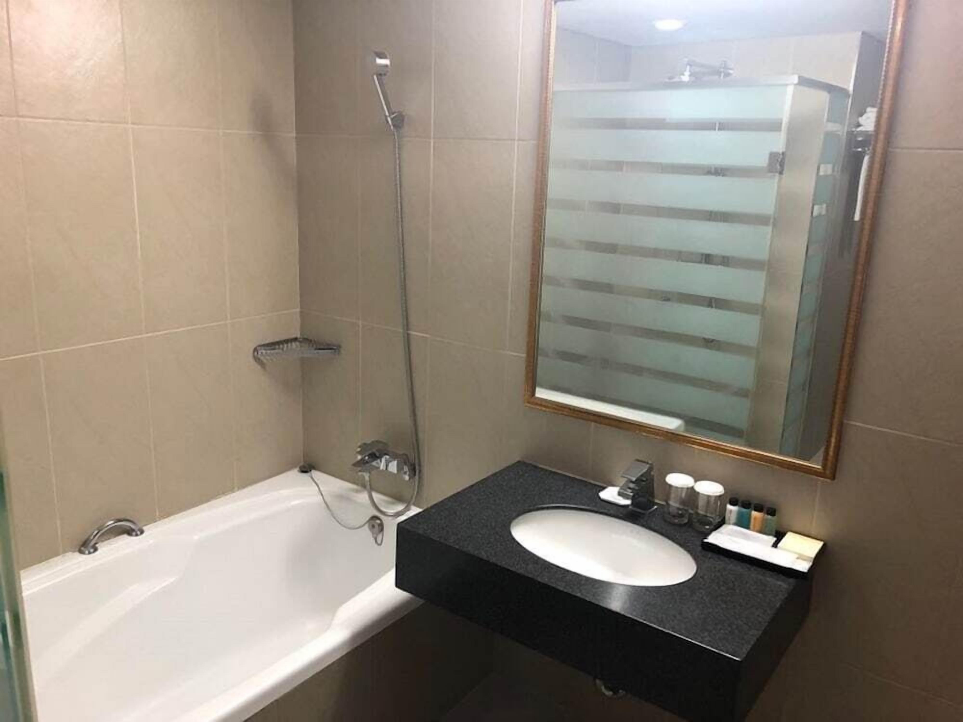 Un baño con bañera, lavamanos y espejo.