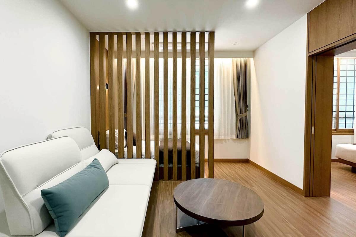 A modern room with a white sofa, a round wooden table, and a wooden partition.