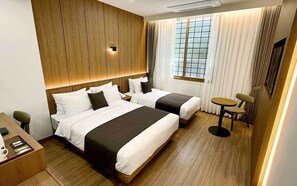 A hotel room with two beds, a desk, and a small table. - Commodore Hotel Pohang (Pohang)