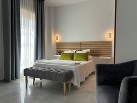 Un dormitorio moderno con una cama, mesitas de noche, un banco y una silla.