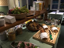 Montaje tipo buffet con diferentes opciones de comida, incluyendo pan, frutas y salsas.