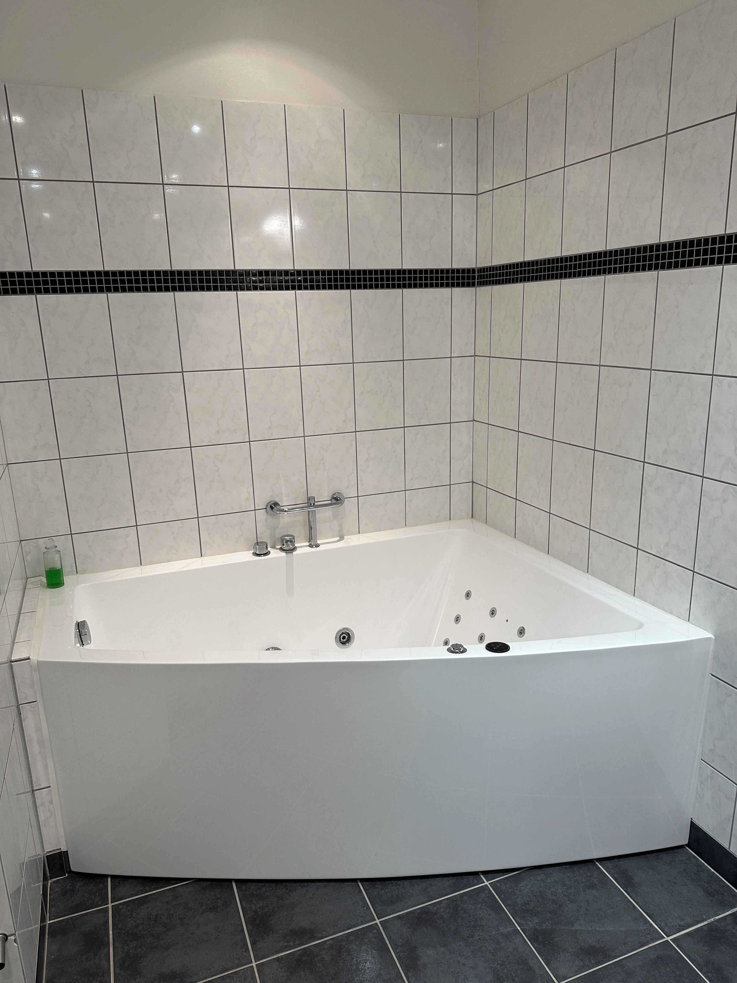 Un baño moderno con una bañera independiente, paredes y piso de baldosas blanco y negro.