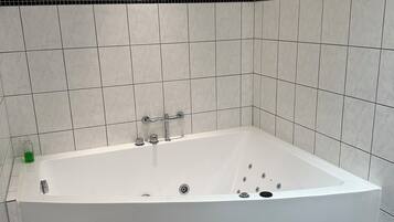 Un baño moderno con una bañera independiente, paredes y piso de baldosas blanco y negro.