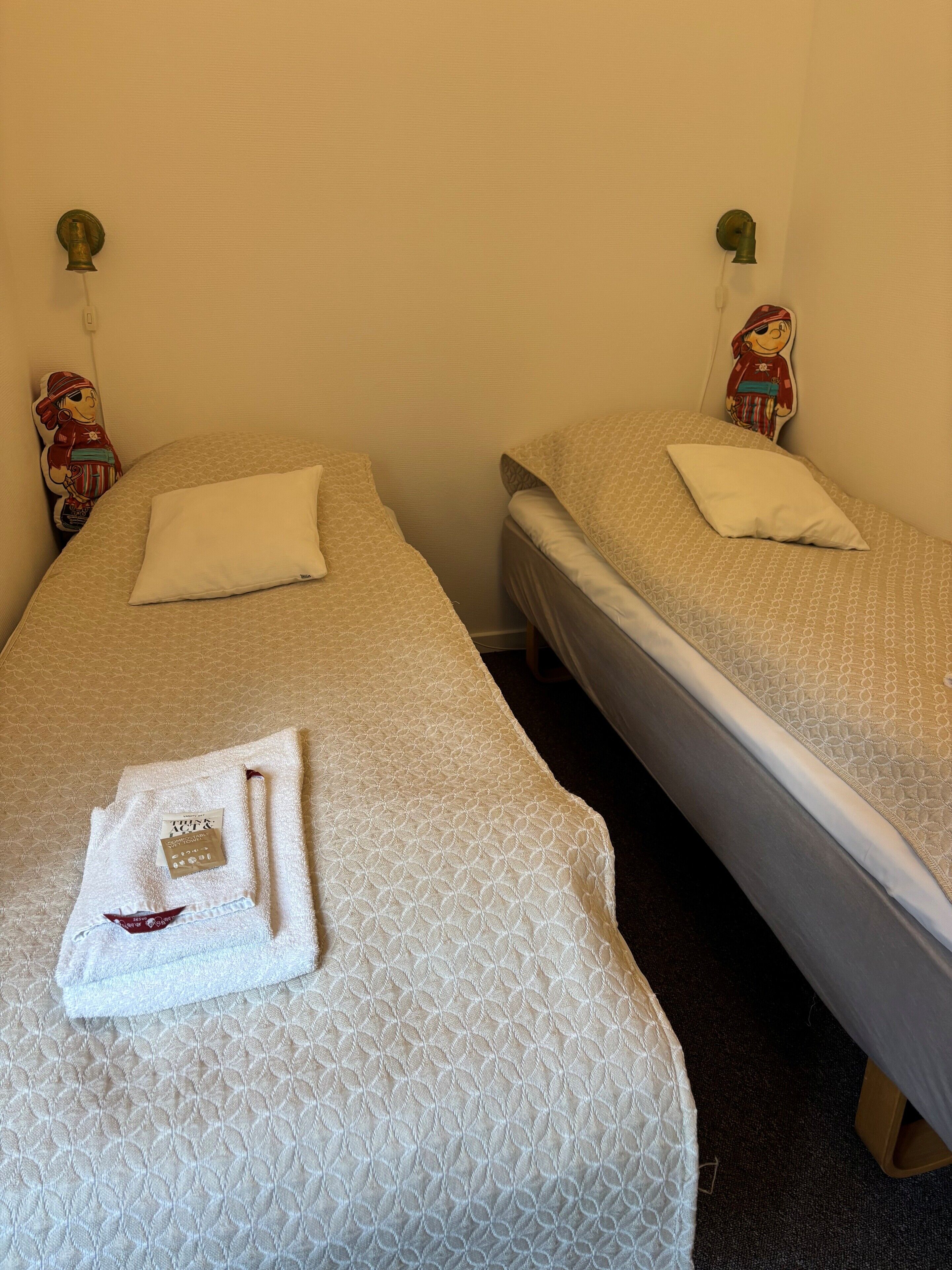 Deux lits simples avec du linge de lit blanc et une serviette sur chacun.