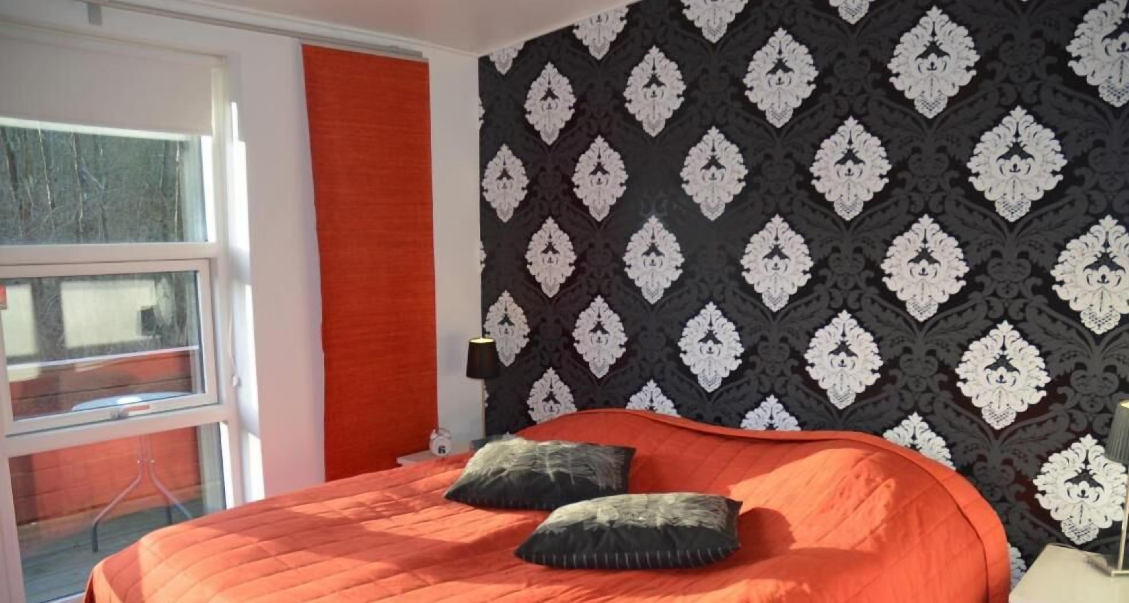 Une chambre à coucher avec un lit, une fenêtre et un mur décoré d’un motif.