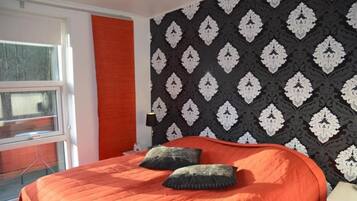 Une chambre à coucher avec un lit, une fenêtre et un mur décoré d’un motif.
