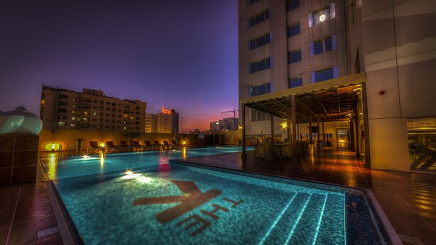 Una piscina con vistas a edificios circundantes y una zona cubierta con asientos.