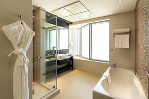 Un baño moderno con ducha envuelta en vidrio, una bañera grande y un tocador con lavamanos.