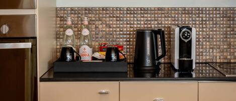 A kitchen counter with a coffee maker, a kettle, and a bottle of water.