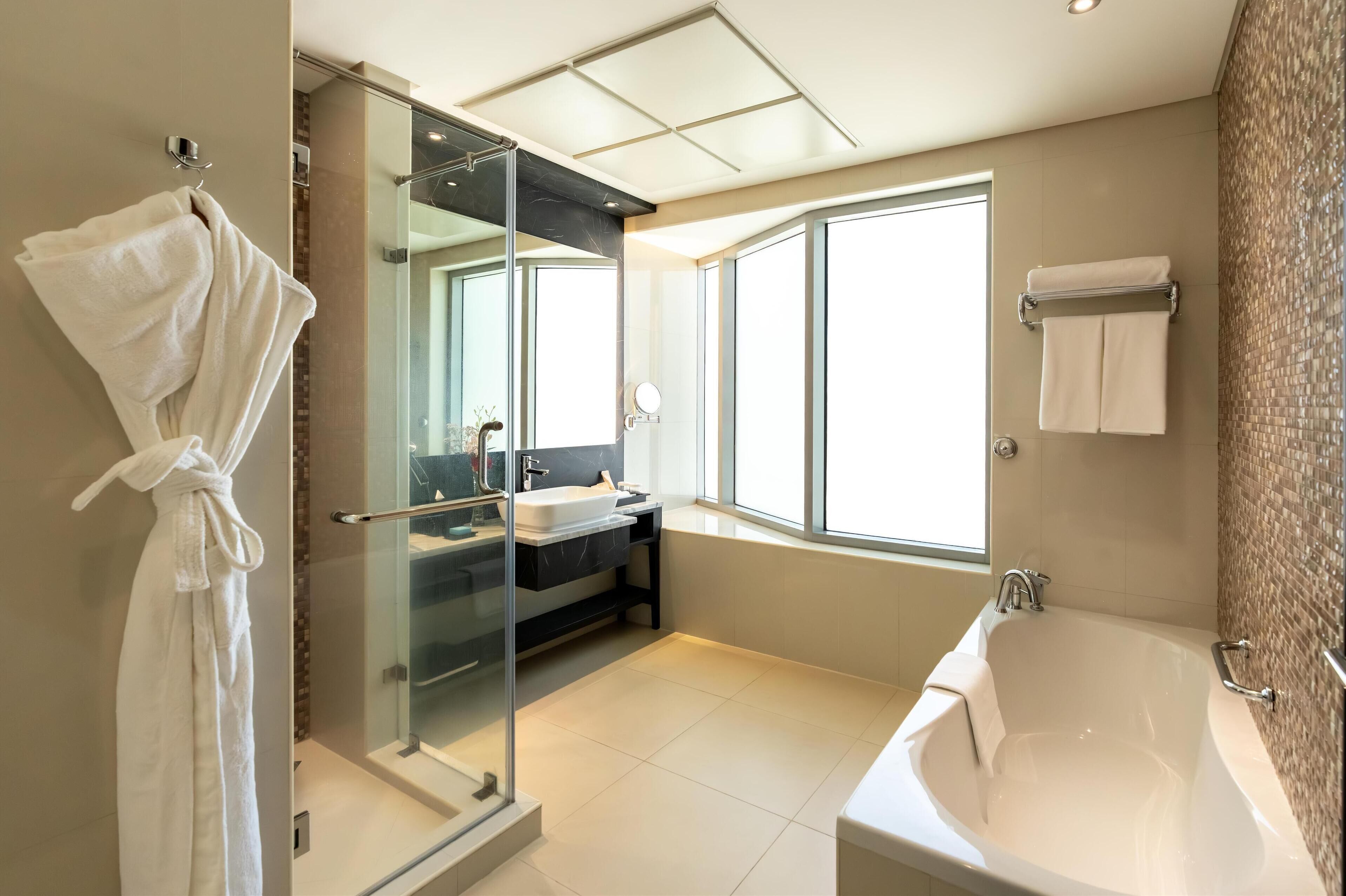 Un baño moderno con ducha de vidrio, una bañera grande y un tocador con lavabo.