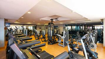 A gym with multiple treadmills, elliptical machines, and weightlifting equipment.