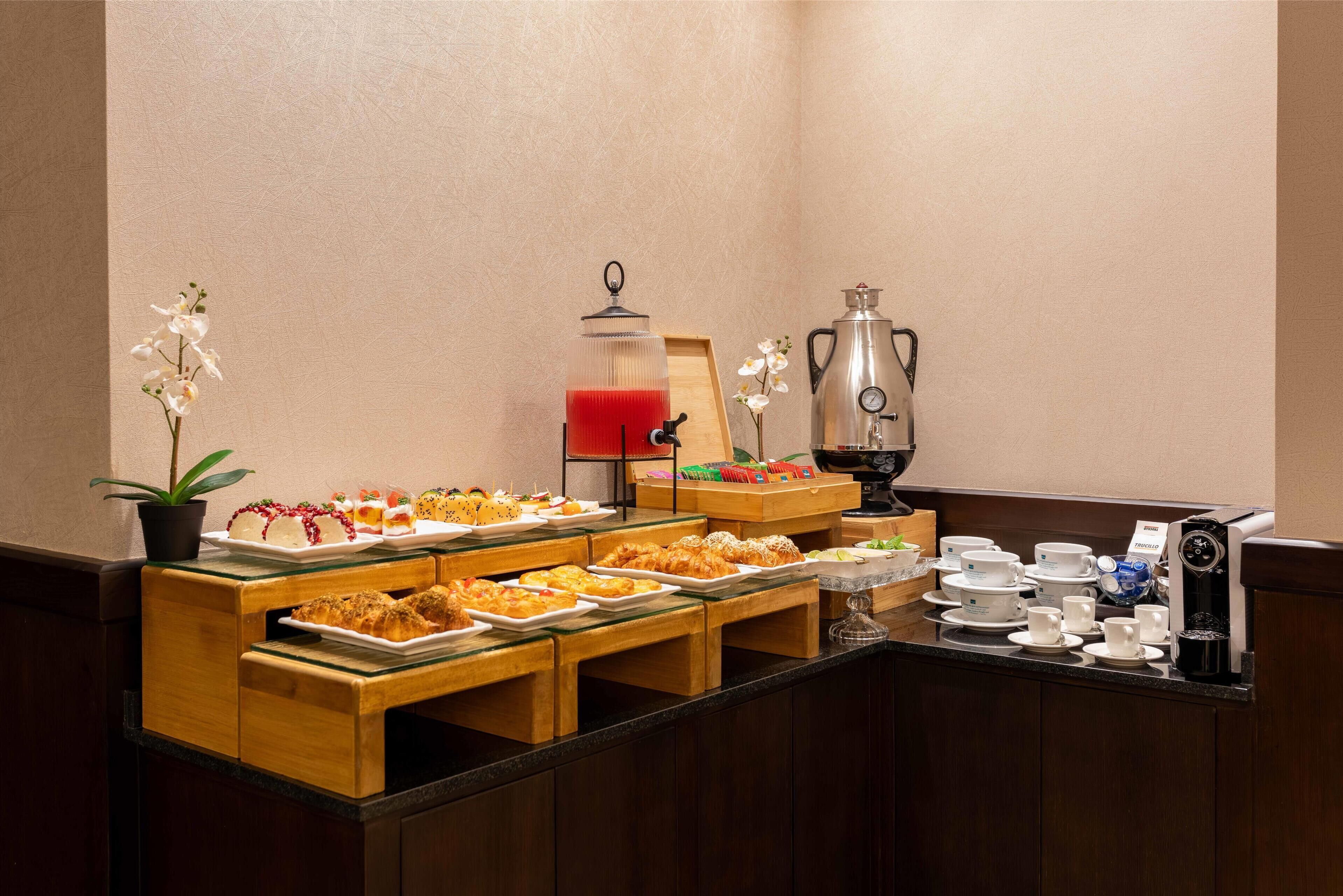 Disposición de bufé con diversas opciones de comida, una máquina de café y una estación de té.