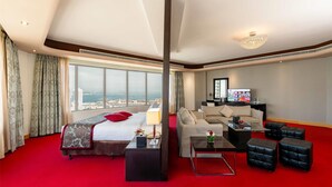 Habitación de hotel con una cama grande, un sofá, una mesa de centro y un televisor.