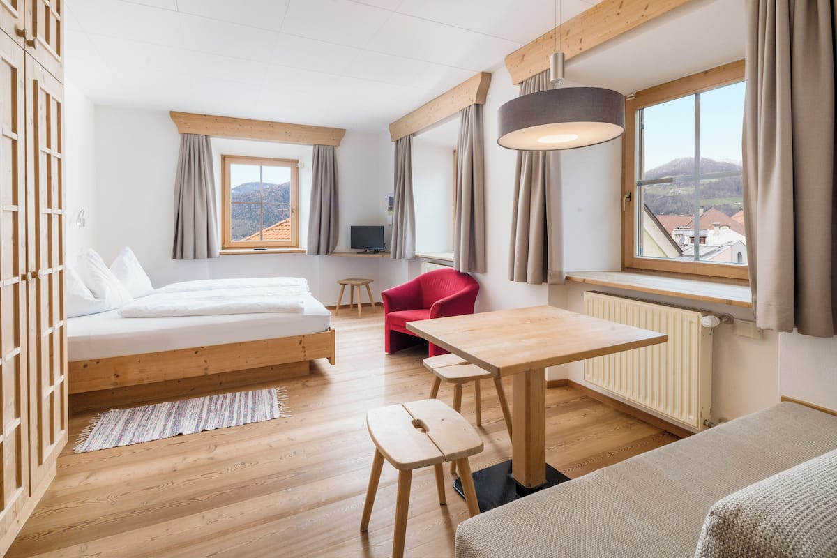 A modern room with a bed, a red chair, a table, and a view of a mountain.