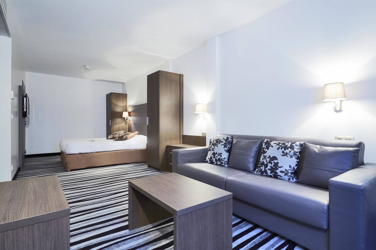 Ein modernes Hotelzimmer mit einem Bett, einer Couch, einem Couchtisch und zwei Wandlampen.