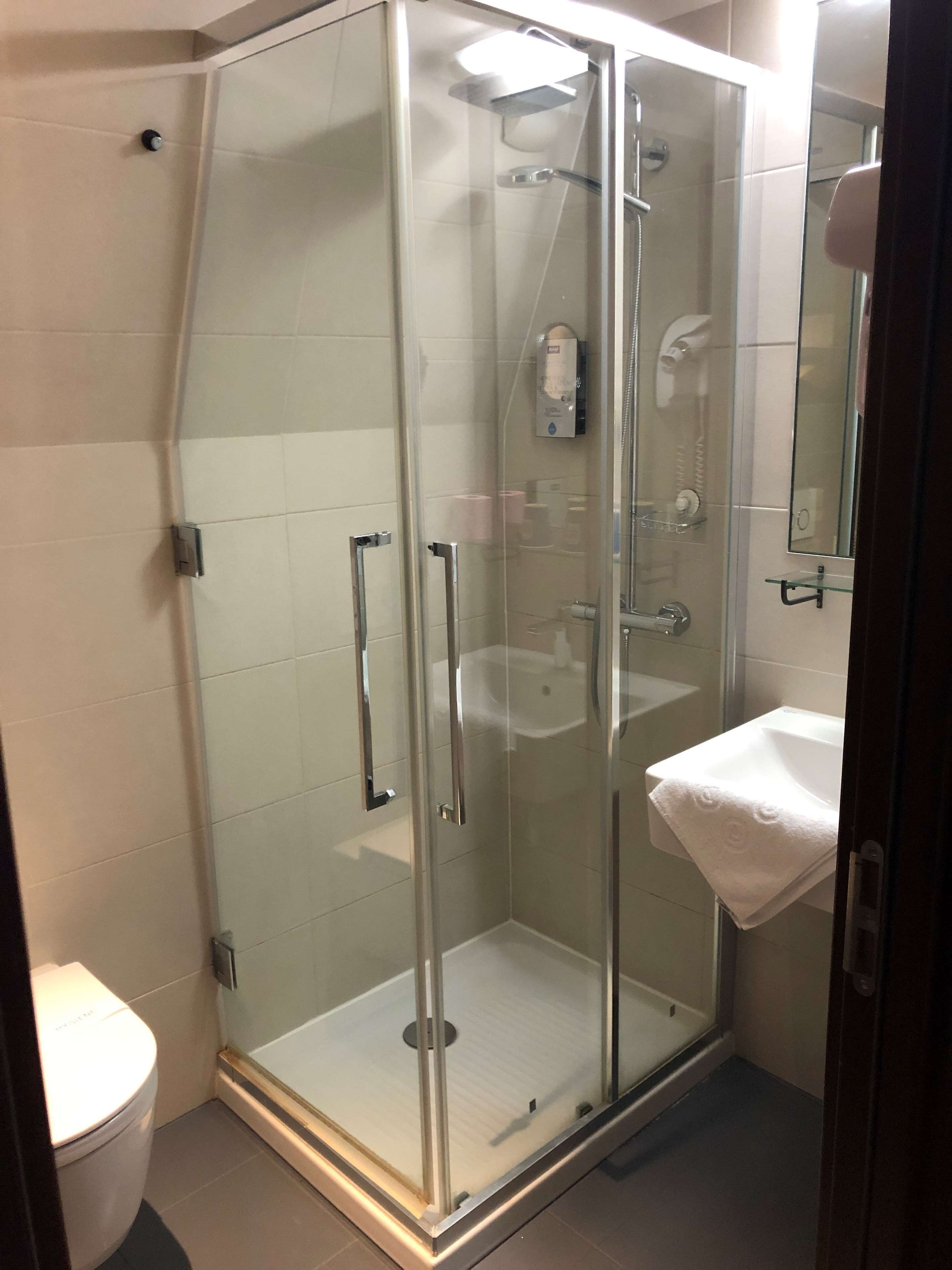 A glass-enclosed shower with a white sink and a toilet.