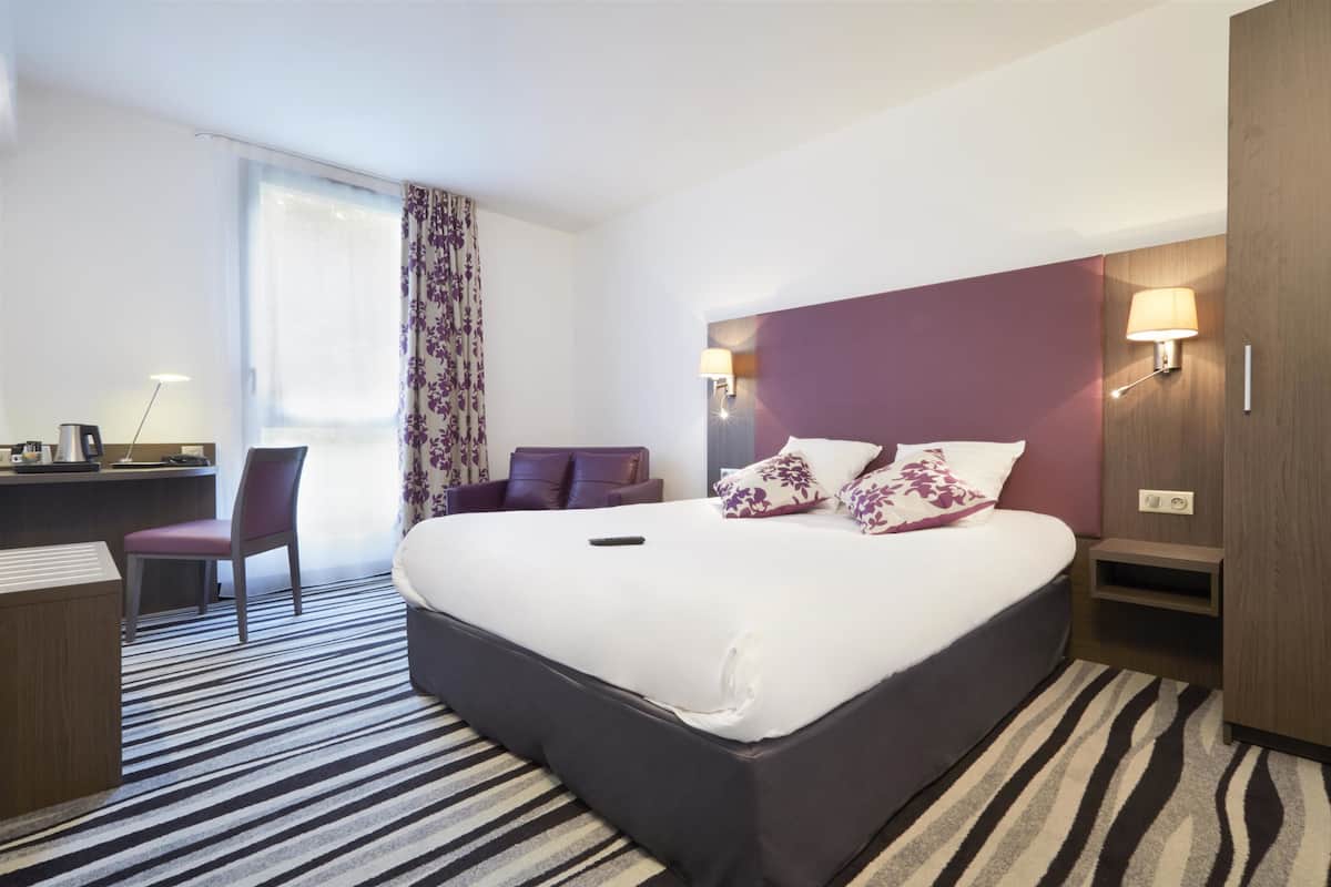 Ein Hotelzimmer mit einem großen Bett, einem Schreibtisch und einem Stuhl.