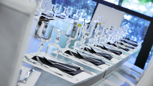 A long table set with multiple wine glasses, plates, and cutlery, indicating a formal dining setup. - Hôtel Kyriad Saint Quentin en Yvelines - Montigny (Montigny-le-Bretonneux)