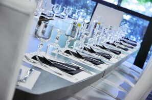 A long table set with multiple wine glasses, plates, and cutlery, indicating a formal dining setup. - Hôtel Kyriad Saint Quentin en Yvelines - Montigny (Montigny-le-Bretonneux)