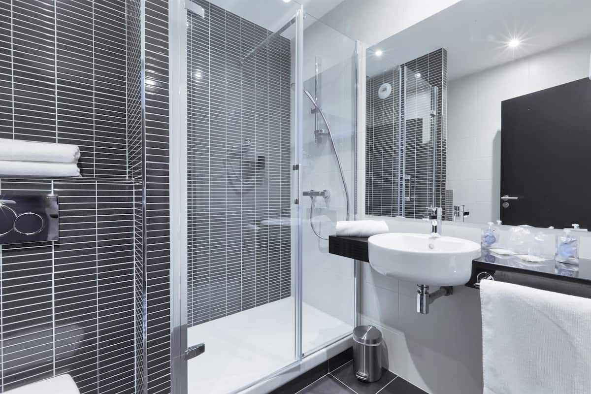 Ein modernes Badezimmer mit einer Duschkabine aus Glas, einem weißen Waschbecken und einer schwarzen Arbeitsplatte.
