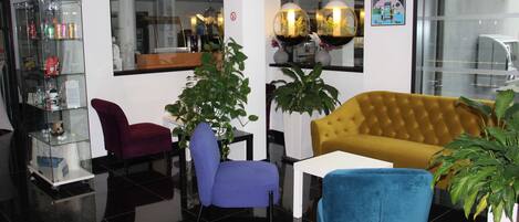 Un vestíbulo moderno con un expositor de vidrio, un sofá amarillo y dos sillones azules.
